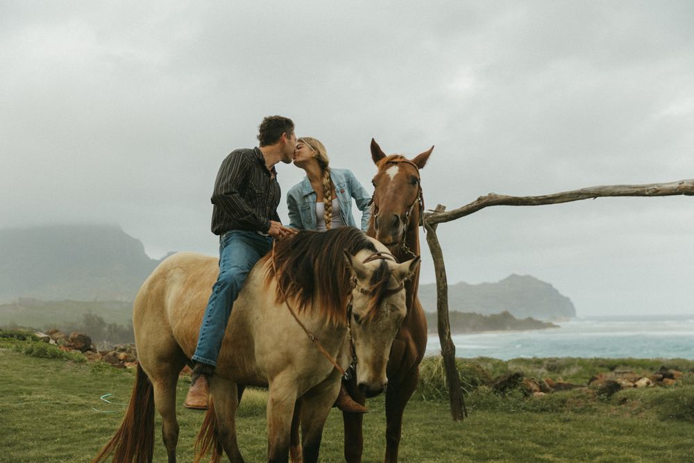 Group of horses and riders enjoying a cloudy day on coastal grasslands.