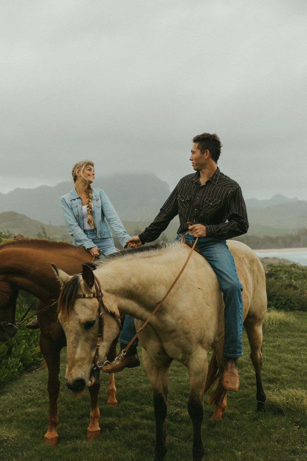 Horseback riders conversing while seated on their mounts in a coastal setting.