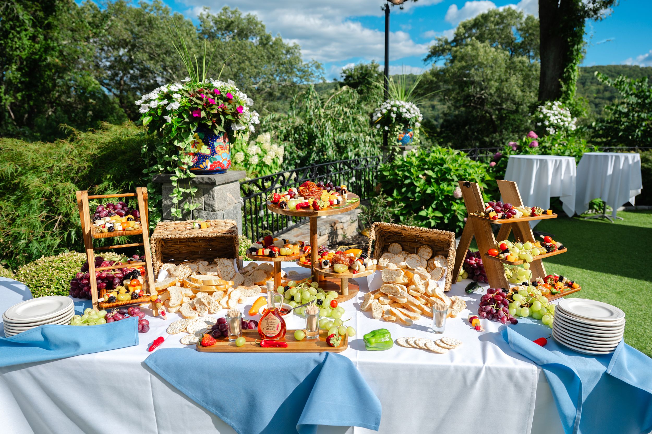 Outdoor cocktail hour display with colorful appetizers, fruits, and snacks arranged on a blue tablecloth at Las Mañanitas in Brewster, NY.