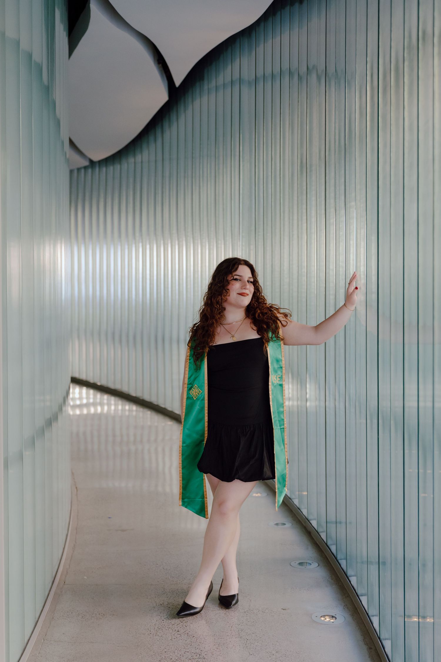 Graduate stands in a hallway of the science building at University of San Francisco. Grad photos taken by Bay Area Graduation Photographer.