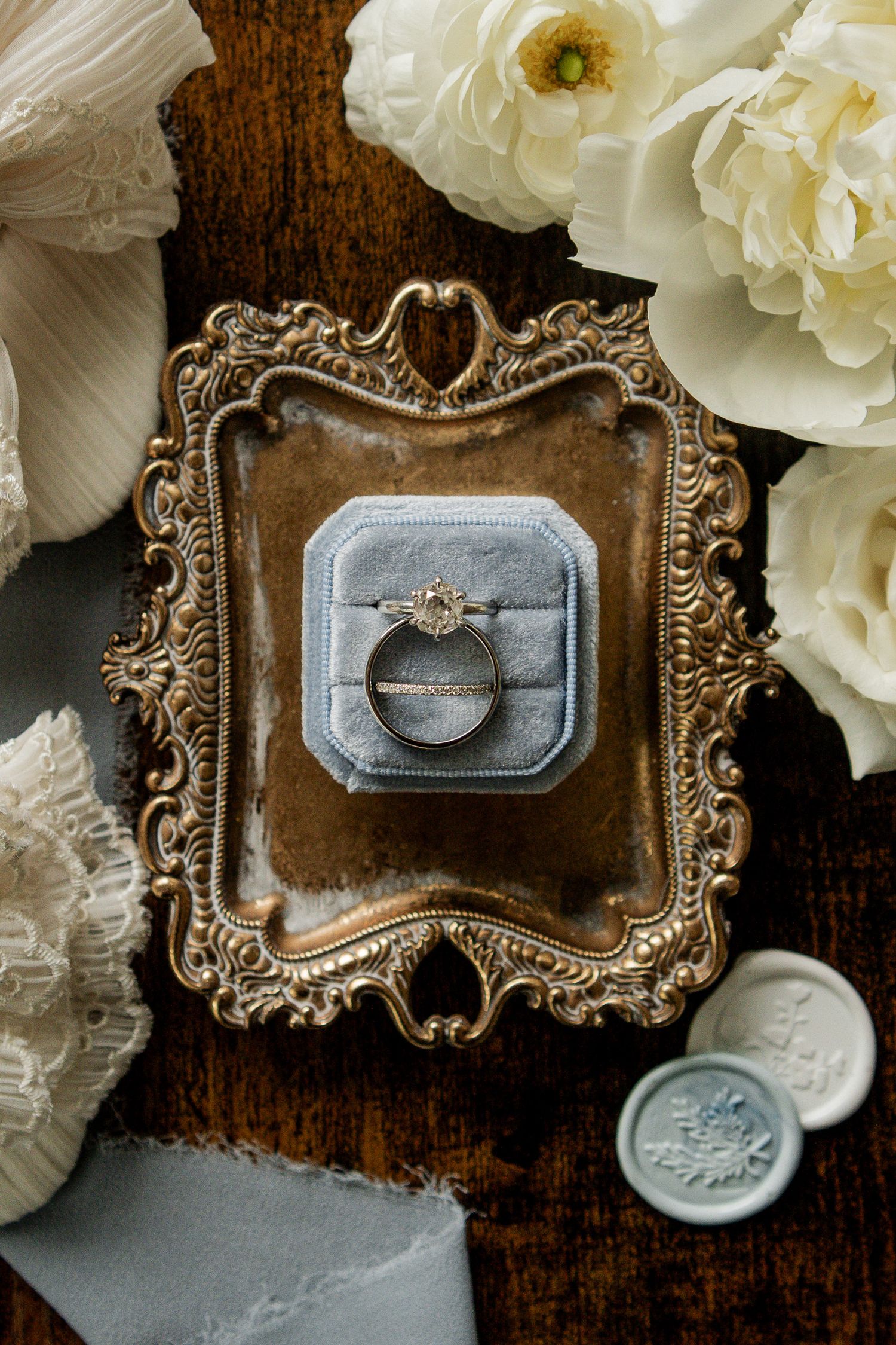 Vintage ornate jewelry box with delicate white peonies and antique brass details on dark wooden surface.