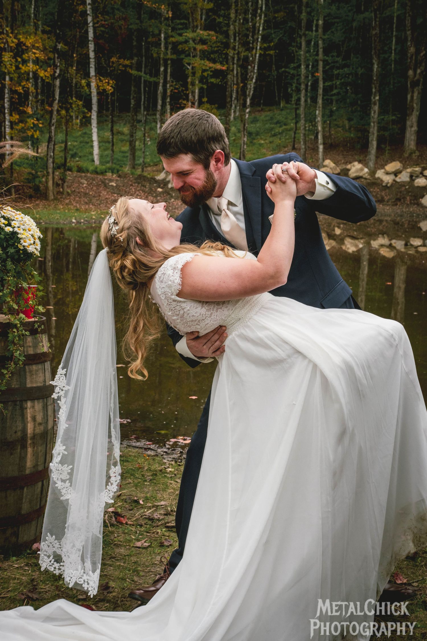 Wedding portrait by Northern Exposure featuring a bride and groom in front of a pond.