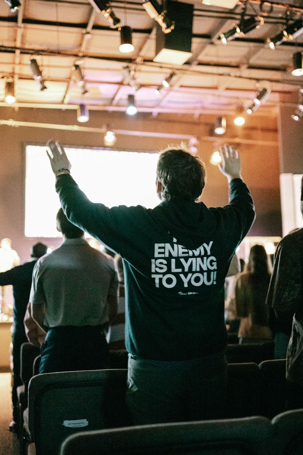young adult worshipping in a Christian hoodie