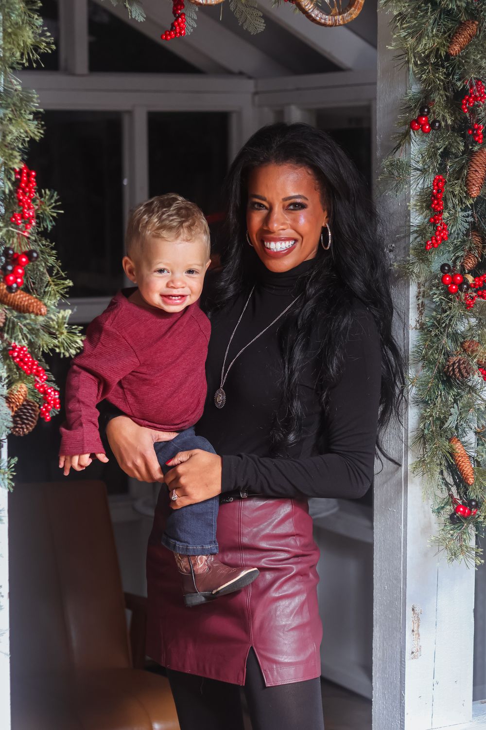 A festive holiday portrait with Christmas decorations and evergreen garlands adorned with red berries and ribbons.