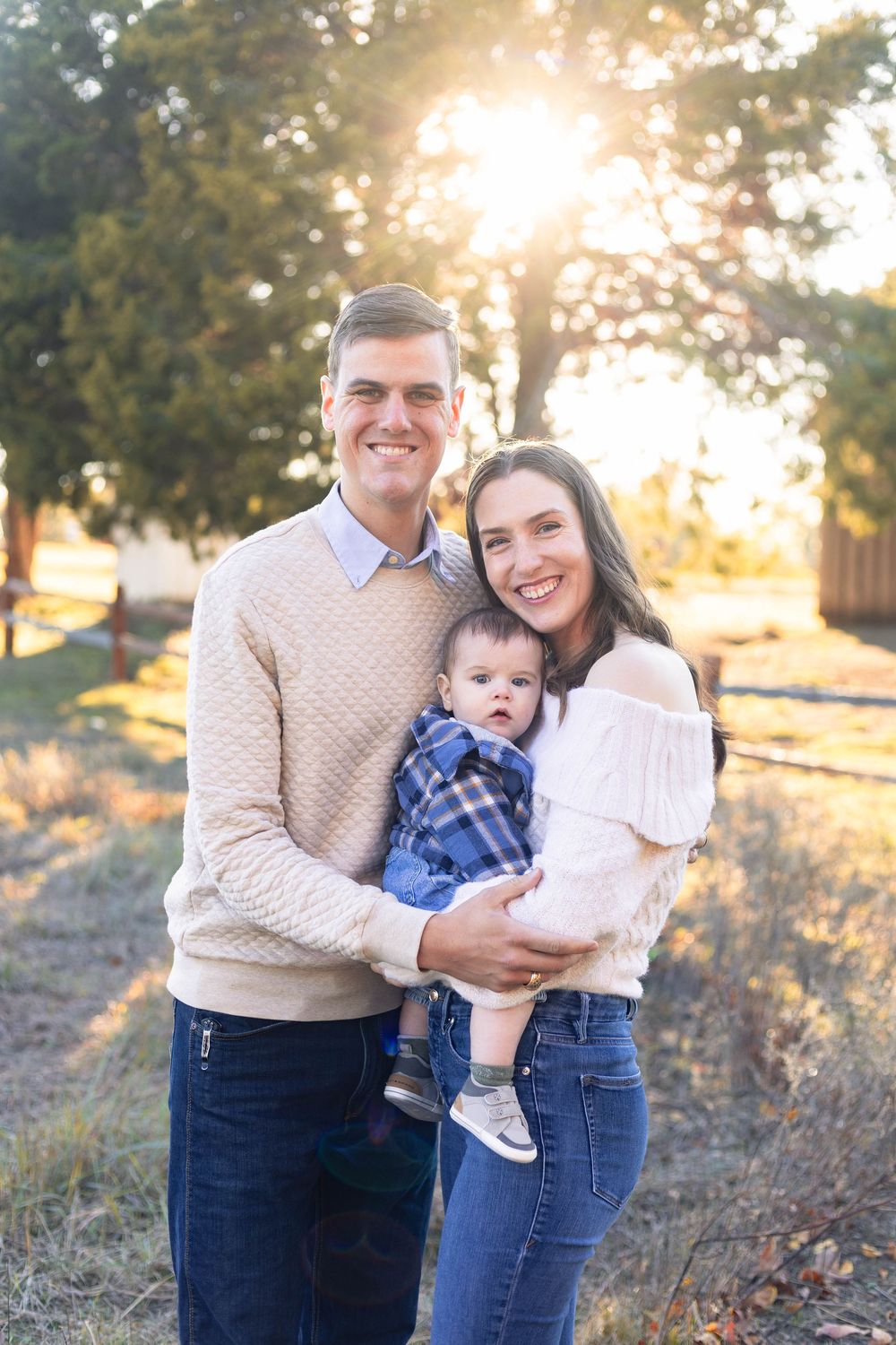 Family enjoying golden sunset outdoors in casual attire during autumn photoshoot.