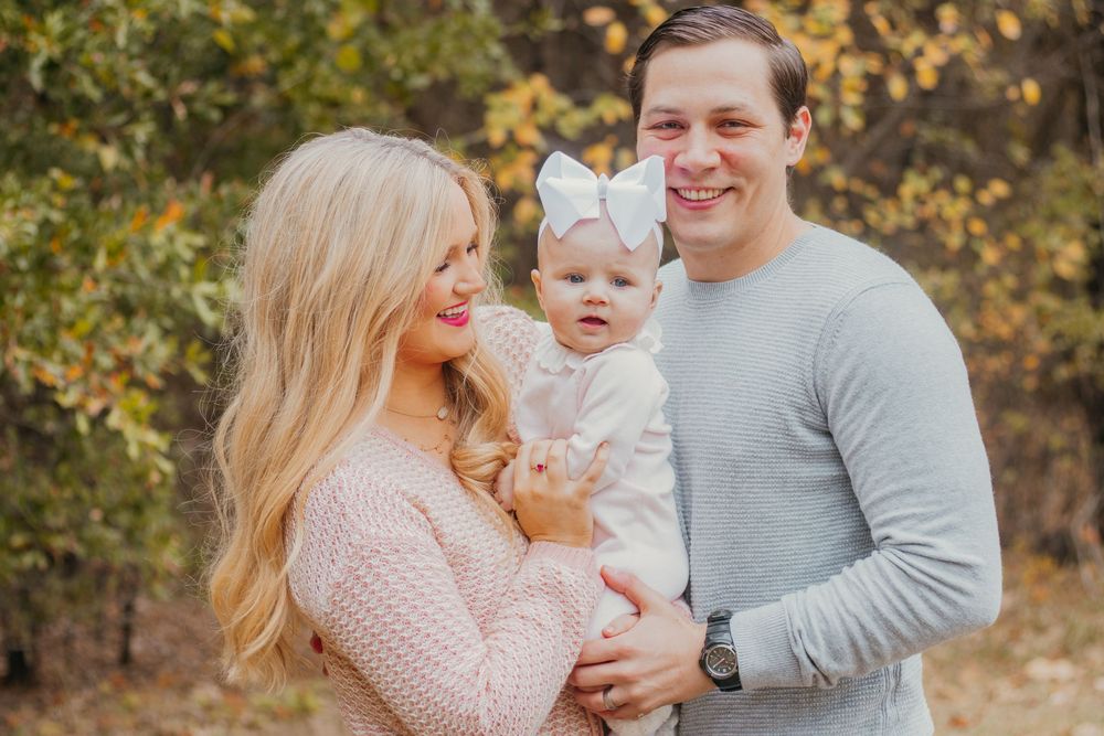 A family shares joyful moments together during an autumn outdoor photo session in a wooded setting.