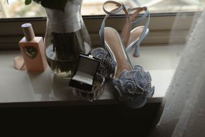 Elegant pale blue wedding heels and accessories arranged on a windowsill.