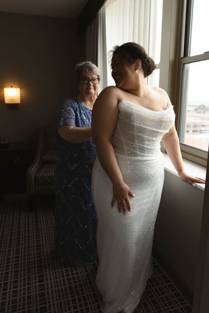 Two people in formal attire standing by a window in an intimate moment.