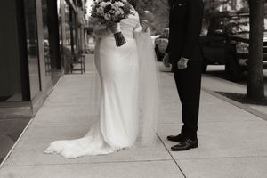 Black and white photo of wedding party walking down urban sidewalk.