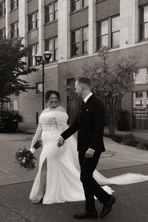A couple sharing a joyful moment together during their wedding photoshoot on a city sidewalk.