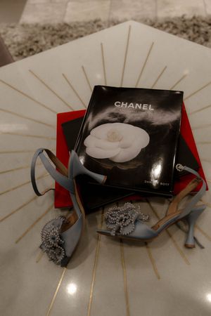 Wedding accessories featuring Chanel box and embellished heels on a decorative surface.