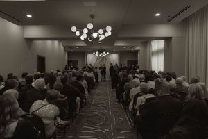 Wide view of a formal event space filled with seated guests and modern decor.