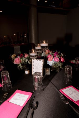Elegant table setting with pink roses, candles and place cards on dark tablecloth.