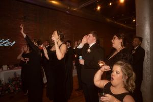 Group of people dancing with hands raised at an evening celebration.