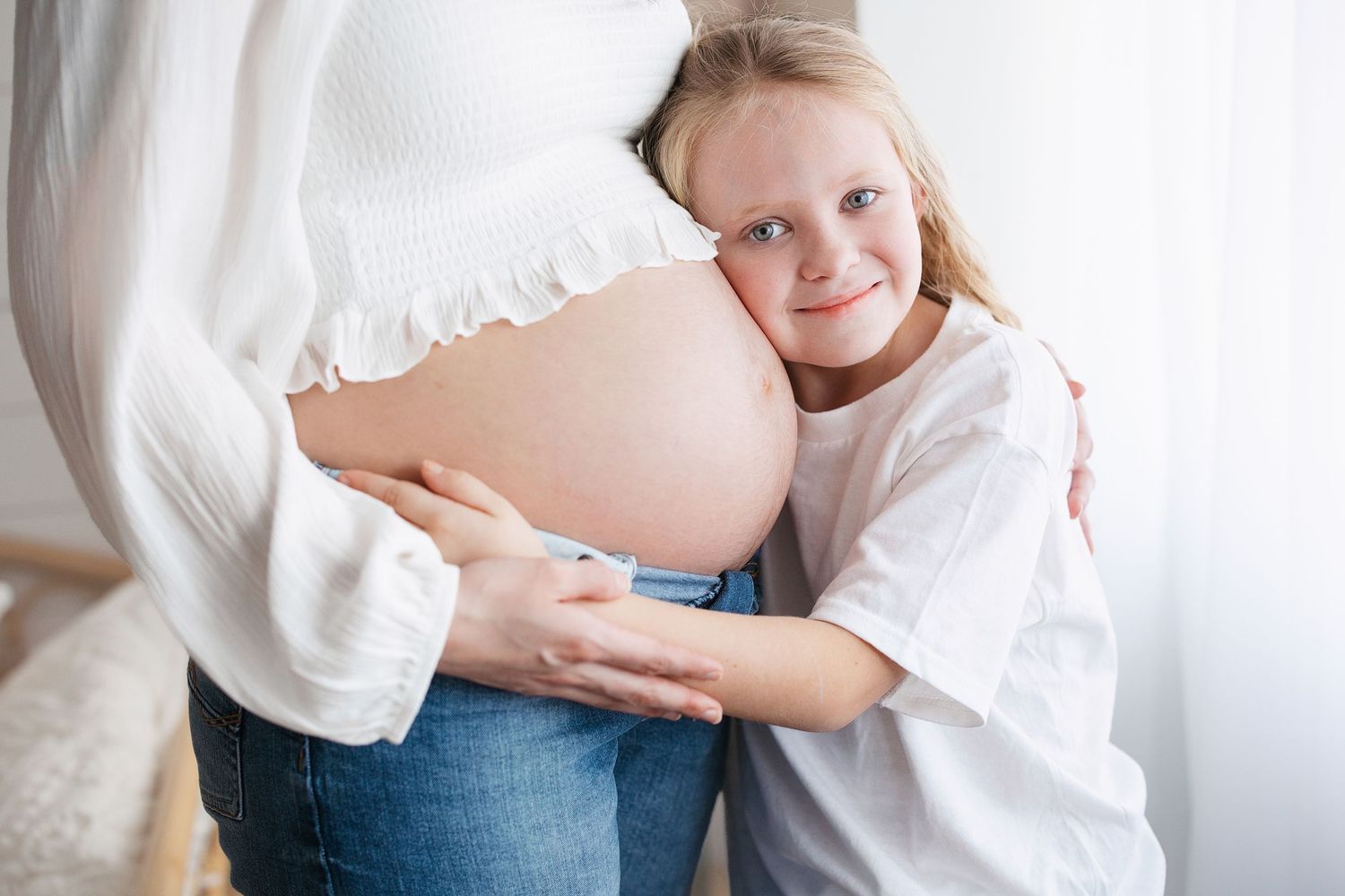 Intimate maternity photoshoot features tender moments in soft white clothing against a light backdrop. Middle TN maternity photos