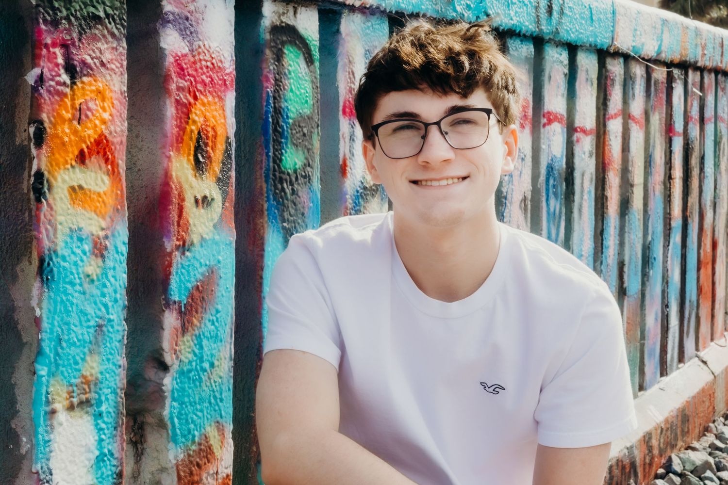 Portrait session against vibrant graffiti wall with bright turquoise and orange colors.