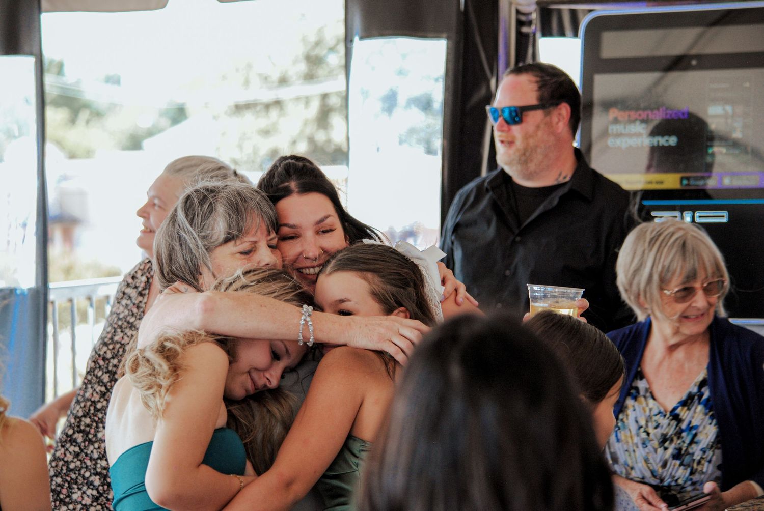 A group of people embrace warmly during what appears to be a celebration or gathering indoors.