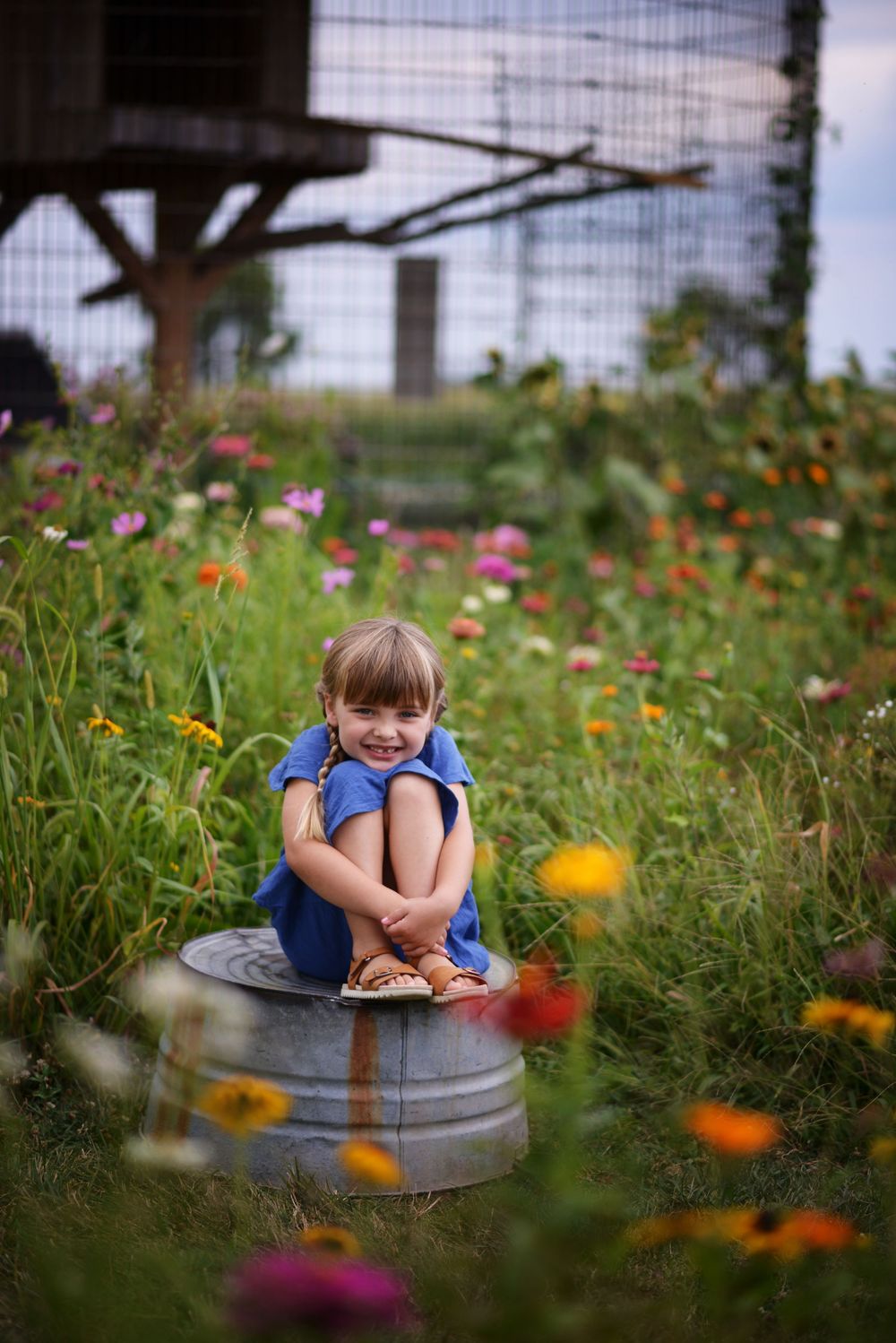 A series of artistic portraits taken in a wildflower garden with metal tubs as props.