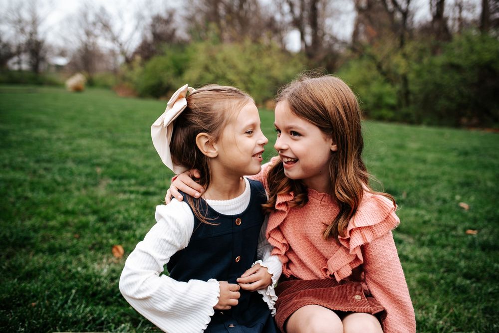 Two children sharing a playful moment together on grass.