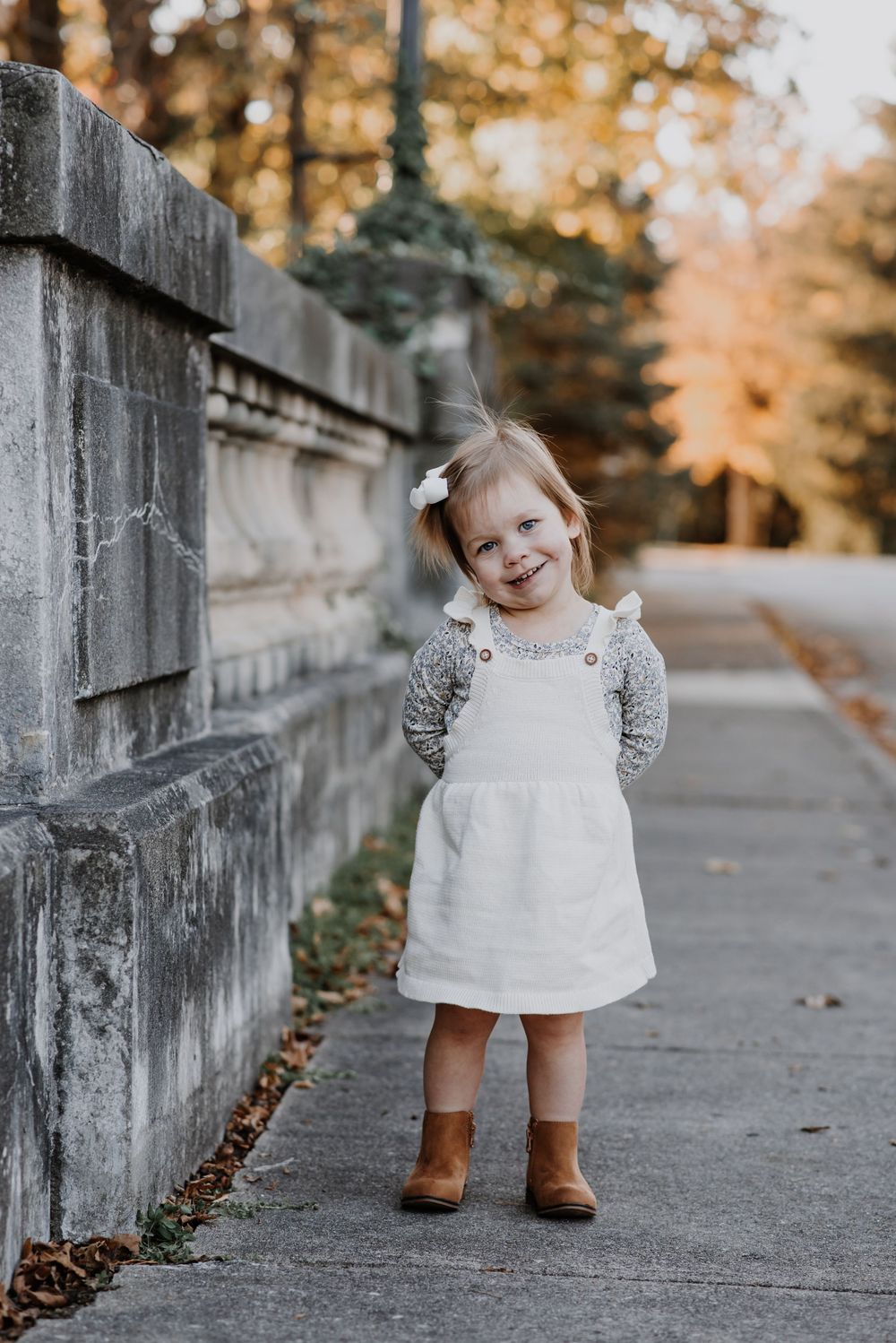 A series of outdoor portraits showing a small child in a white dress walking along a concrete path.