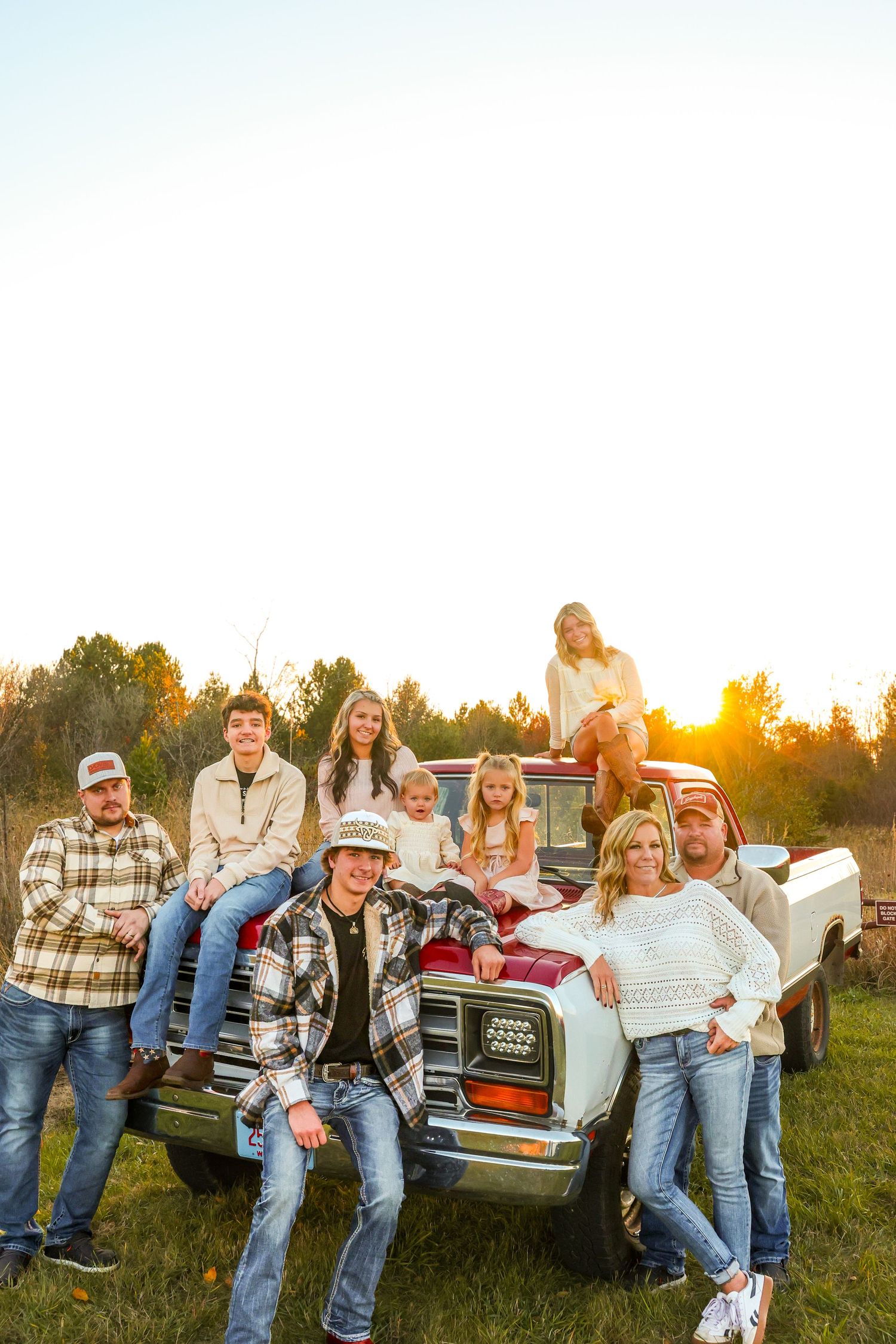 Family sitting on classic truck during golden hour, family photographer.