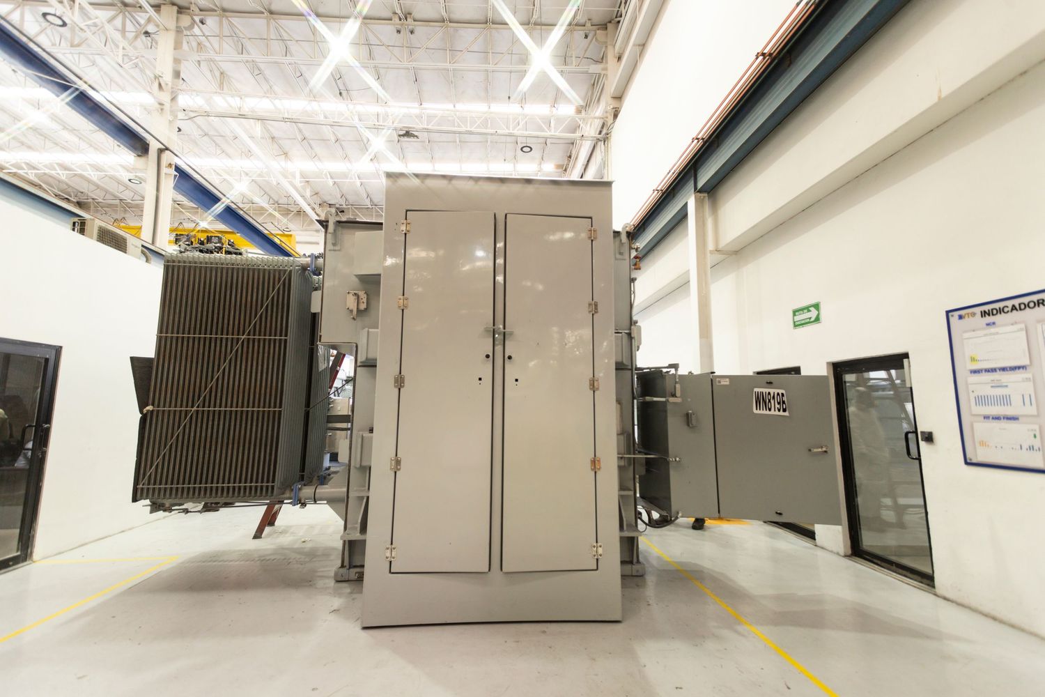 Industrial warehouse interior with rows of metal storage units and equipment mounted on walls.