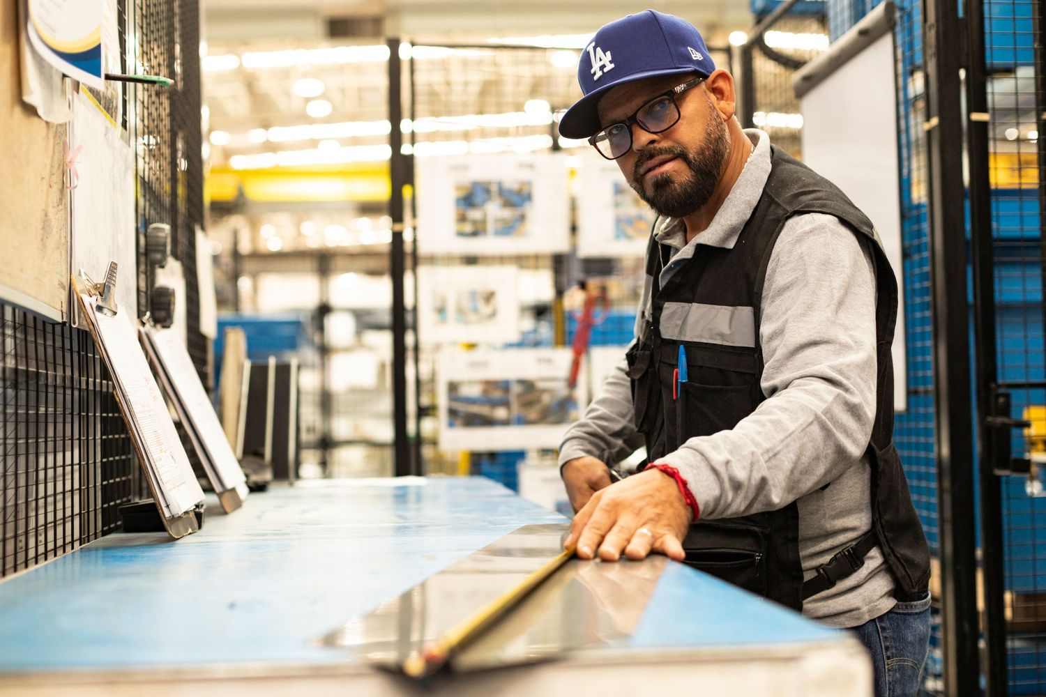 Worker operating equipment in a modern manufacturing facility with bright lighting and blue accents.