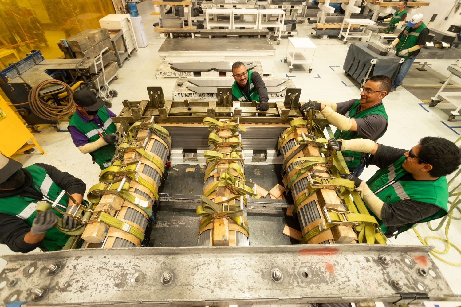 Factory workers assembling products on a production line with yellow packaging materials.