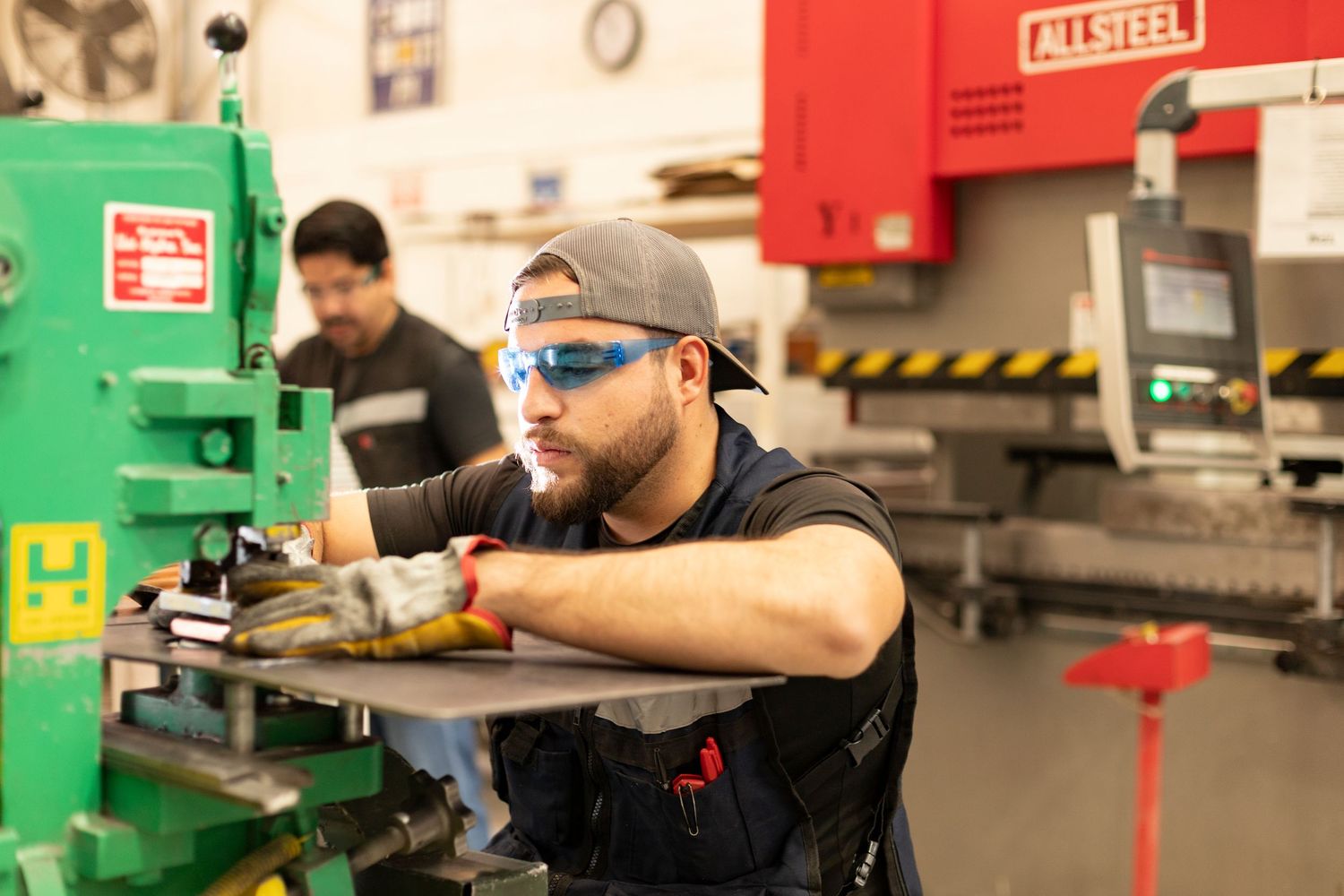 Students work on machinery and equipment in a technical training facility with red and green industrial equipment.