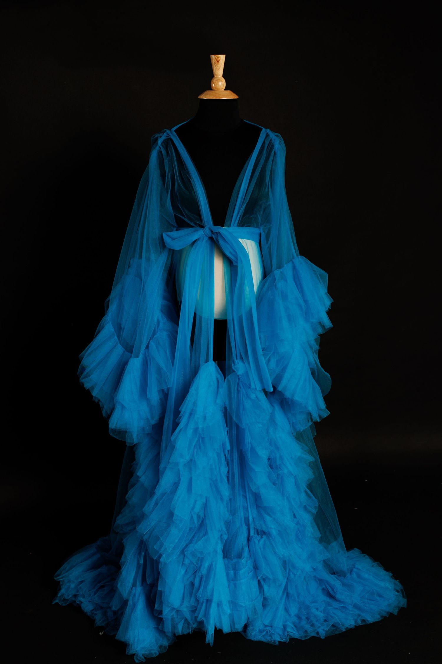 A dramatic turquoise blue tulle robe with billowing sleeves photographed against a black background in multiple angles.