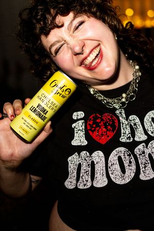 Photograph of queer event attendee wearing bedazzled "I heart hot moms" shirt at New York City brand activation party.