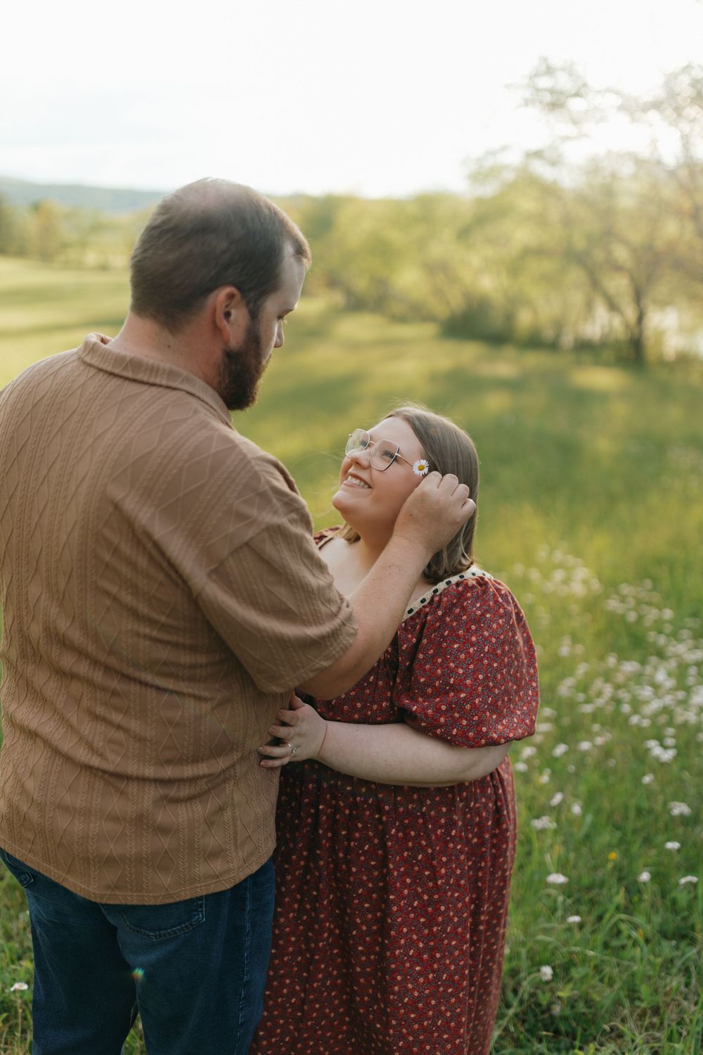 A couple shares an intimate moment in a wildflower meadow during golden hour.