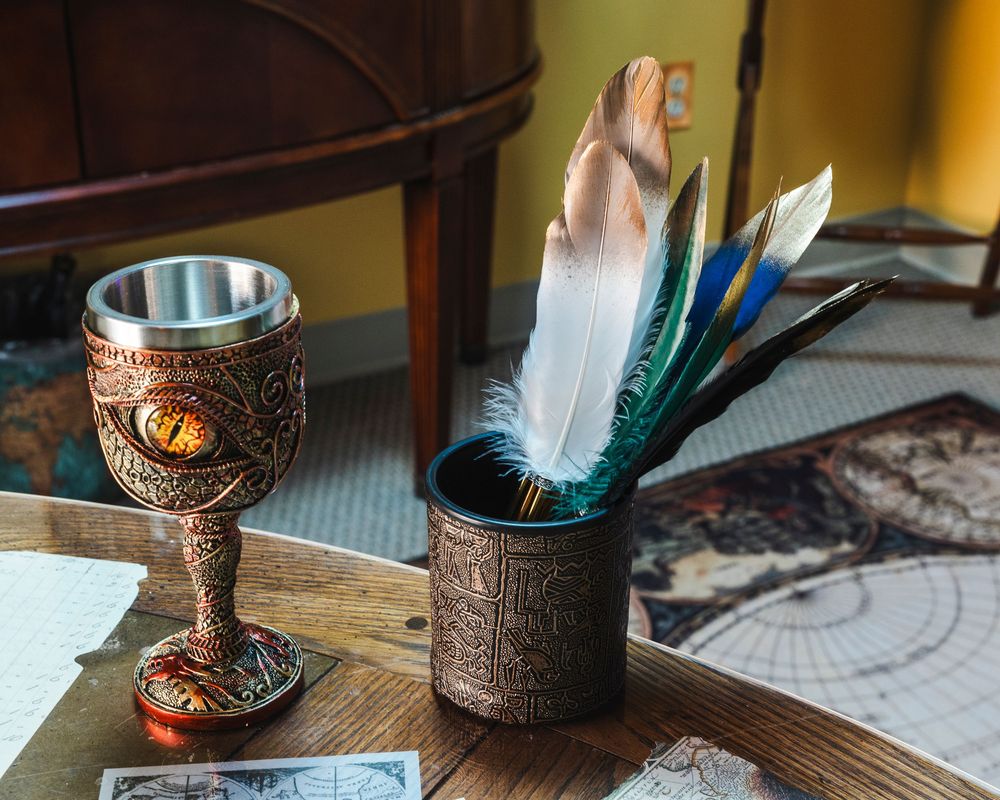 A collection of wooden and metal goblets with ornate designs arranged on a rustic table surface.