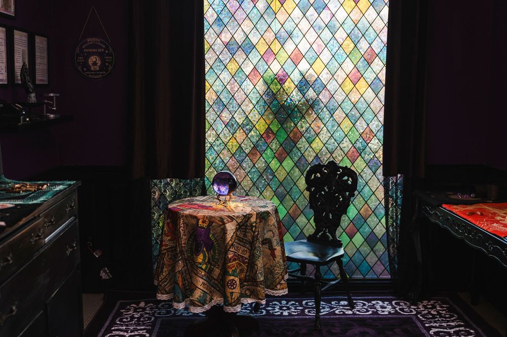Colorful diamond-patterned stained glass window creates a vibrant backdrop in a dimly lit interior space.