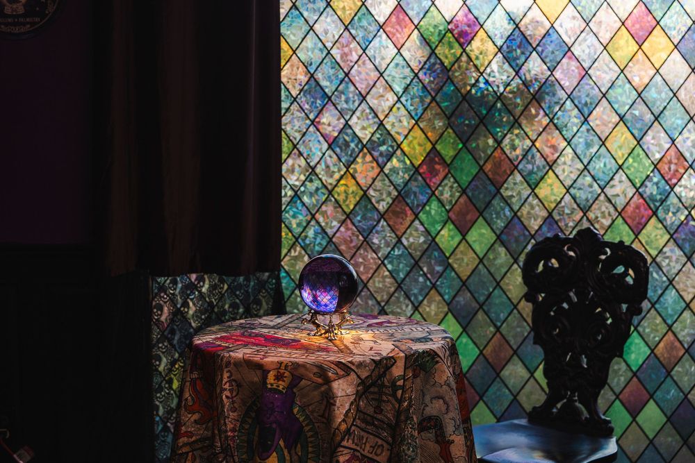 Colorful stained glass diamond pattern window creates a vibrant mosaic backdrop with multicolored geometric shapes.