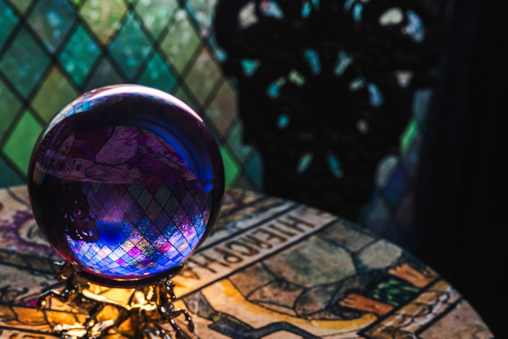 Crystal ball glows with blue and purple reflections while resting on decorative cards in mystical setting.