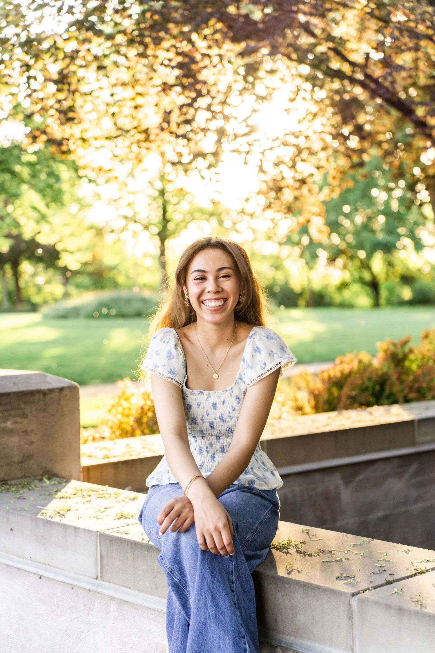 Portrait of woman in white dress sitting outdoors during golden hour at the BYU Campus in Provo, Utah.