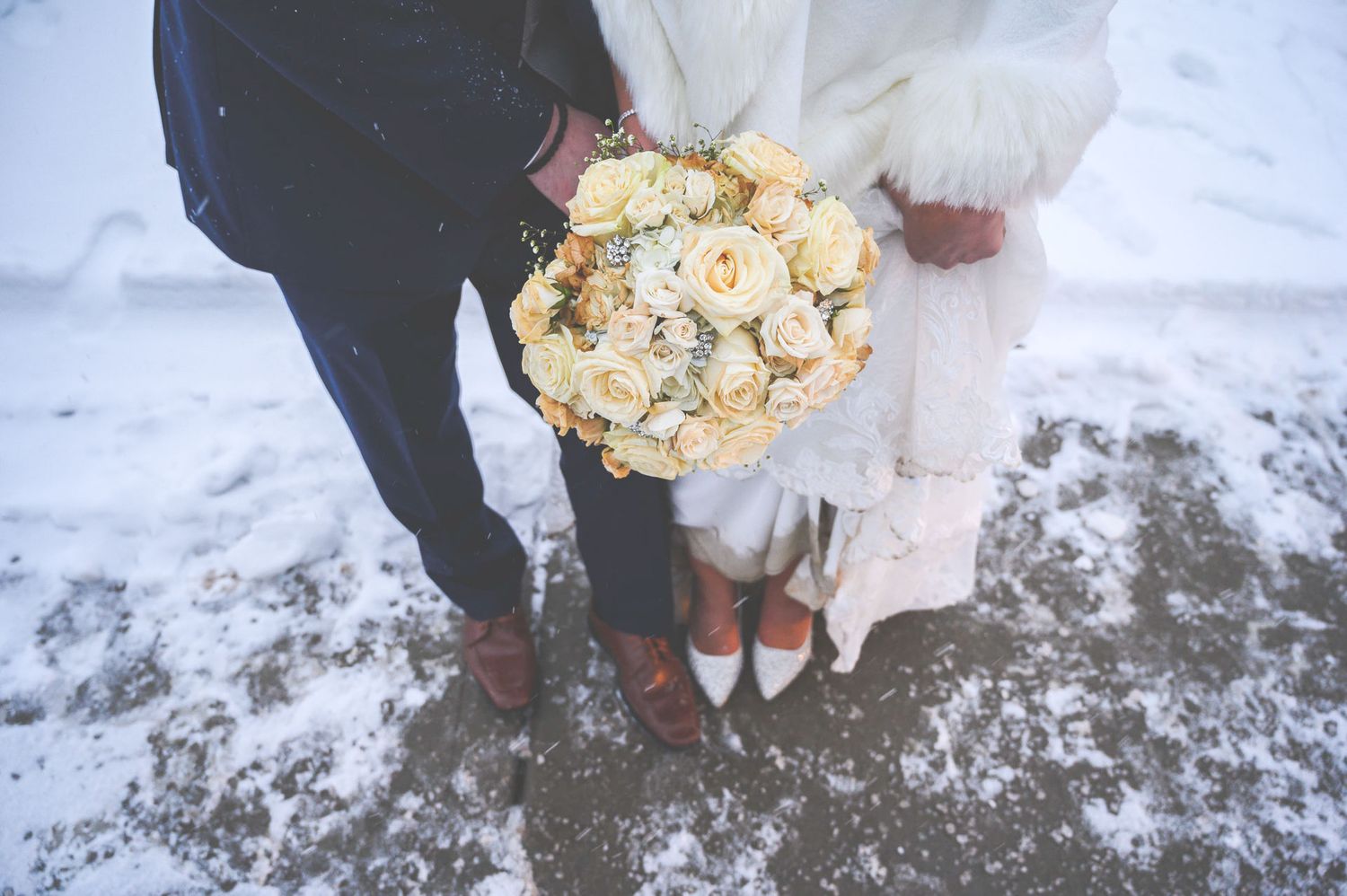 Hands holding white and brown speckled eggs in a snowy winter setting.