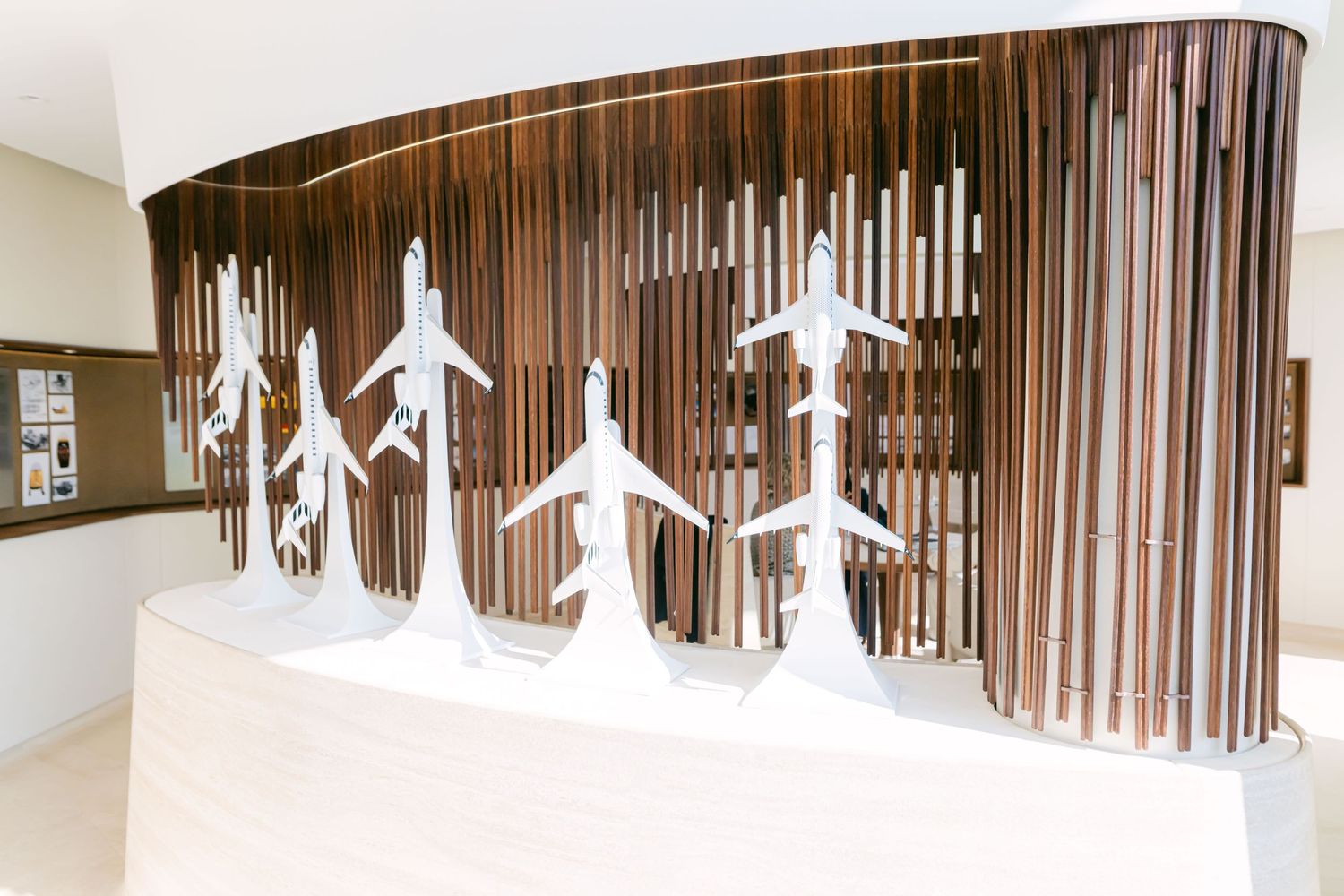 Modern clothing store interior with hanging white garment displays and vertical wooden slat wall panels.