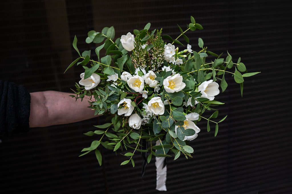 White and green sustainably sourced bouquet held against a black background