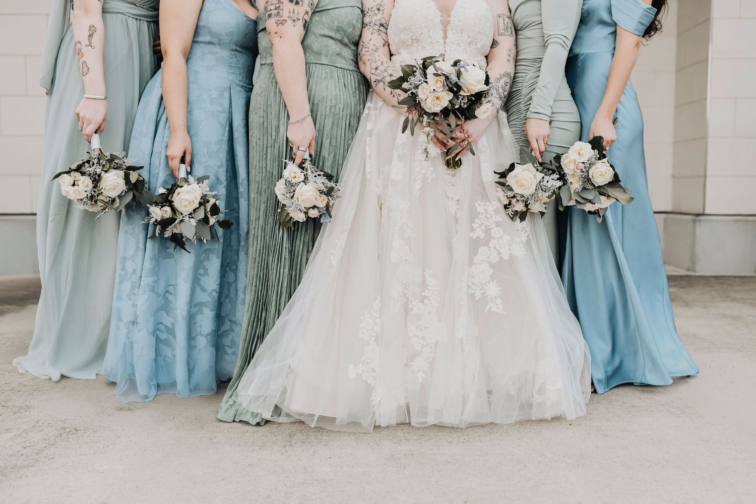 Mixed and matched bridesmaids wearing powder blue and sage dresses for a winter wedding