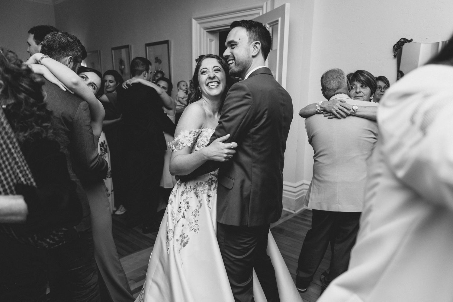 Wedding guests dancing and celebrating together on the dance floor at an indoor reception.