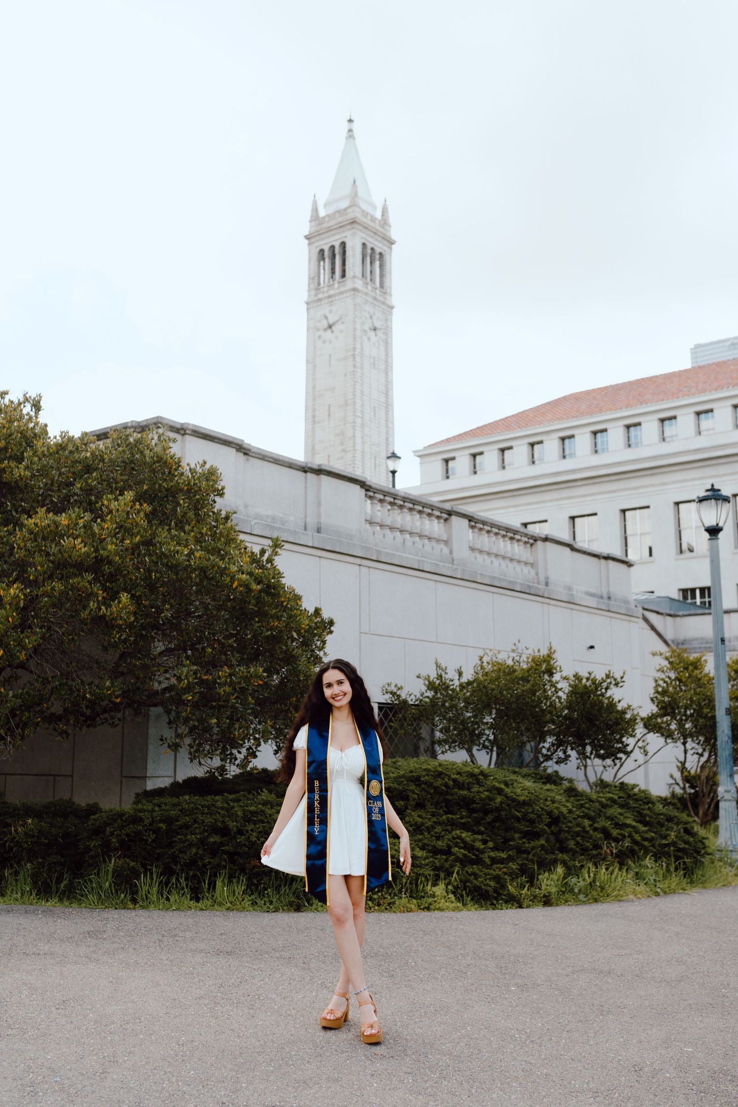 UC Berkeley graduate poses outside the campus's iconic Campanile (Sather Tower) for her grad photoshoot.