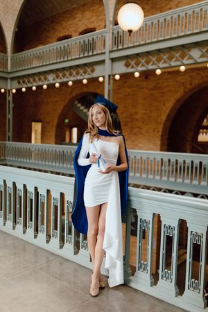 UC Berkeley graduate wears a white dress and poses elegantly for her graduation photoshoot inside Hearst Memorial Mining Building on campus.
