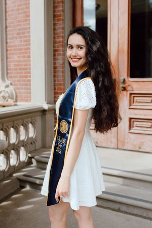 UC Berkeley graduate poses outside one of the campus's beautiful buildings for her grad photoshoot.