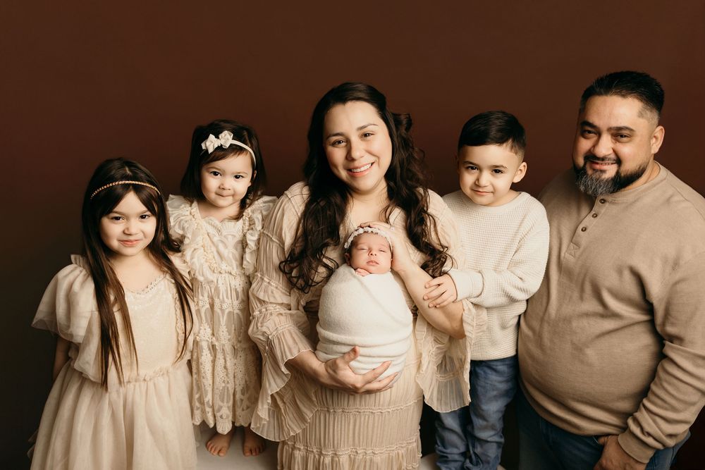 Family wearing neutral toned outfits poses together in a series of connected portrait photographs.