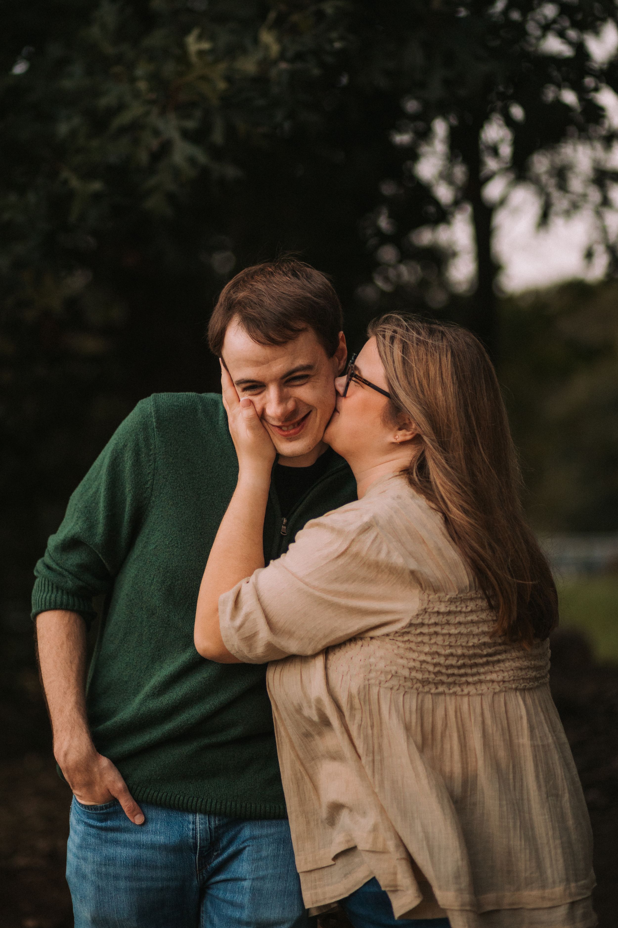 A romantic couple shares an intimate moment outdoors wearing green and beige outfits.