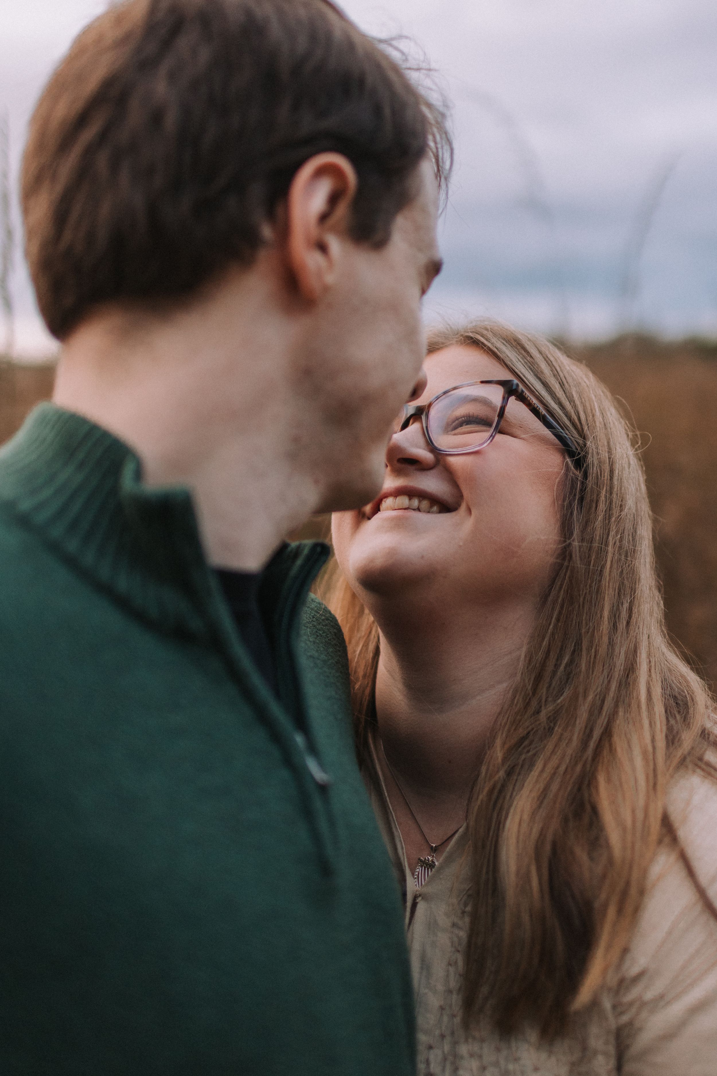 Close-up shot of a couple sharing a loving moment against a cloudy sky.