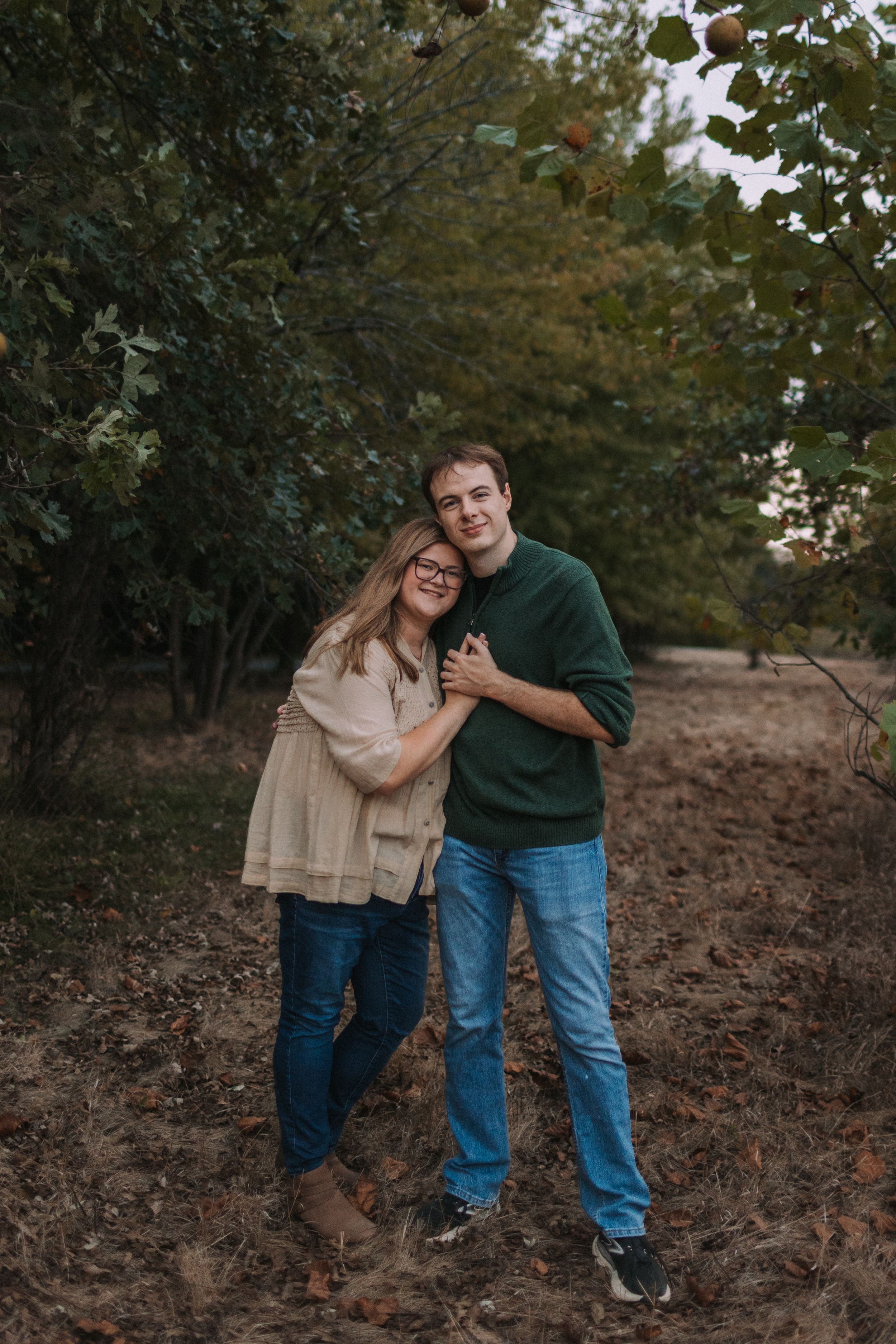 A couple shares playful moments on a hillside during an autumn photoshoot.
