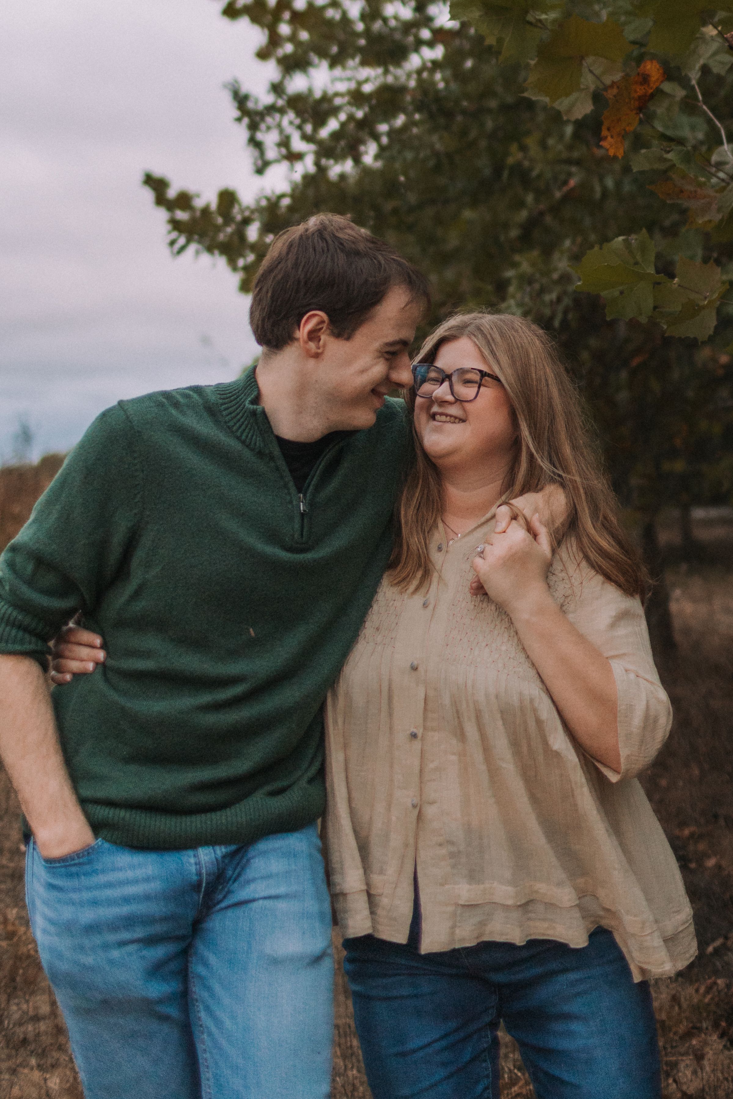 A couple in casual wear shares candid moments during an outdoor photo session.
